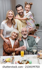 Cheerful Family Looking At Camera Near Table With Easter Dinner