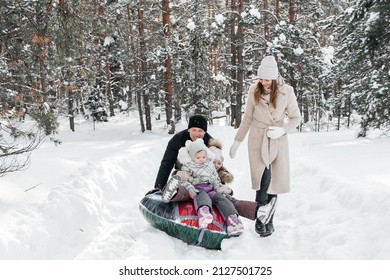 Cheerful Family On A Weekend Rides A Sleigh In A Snowy Forest. High Quality Photo