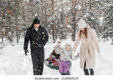 Cheerful Family On A Weekend Rides A Sleigh In A Snowy Forest. High Quality Photo