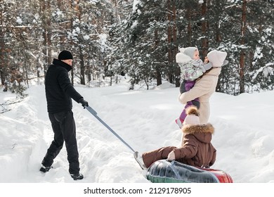 Cheerful Family On A Weekend Rides A Sleigh In A Snowy Forest. High Quality Photo