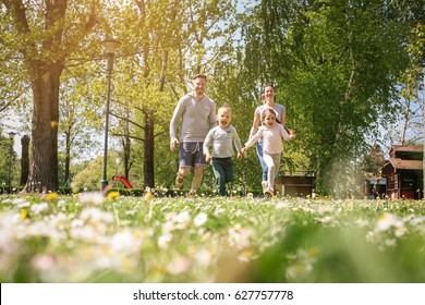 Cheerful Family Playing With Their Children's In The Meadow. Family Having Fun In Spring Day.