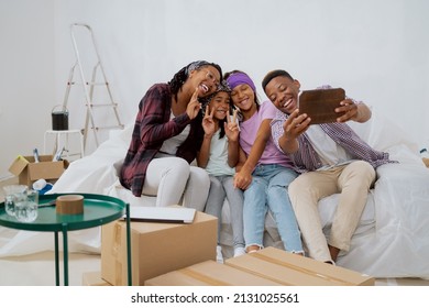 Cheerful family renovates a new apartment, laughing dad takes a selfie with his wife and kids, daughters fool around, pose for a photo, funny team - Powered by Shutterstock