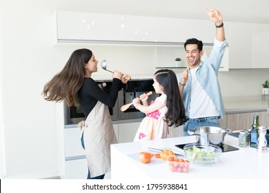 Cheerful Family Singing And Dancing While Cooking Food In Kitchen