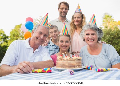 Cheerful Family Smiling At Camera At Birthday Party Outside At Picnic Table