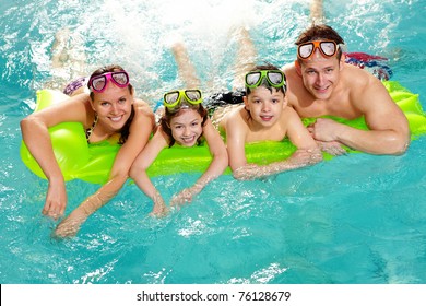 Cheerful Family In Swimming Pool Smiling At Camera