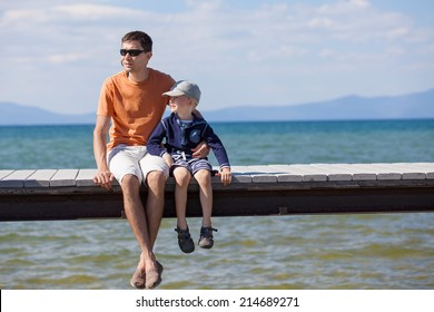 Cheerful Family Of Two Sitting At The Dock During Vacation At Lake Tahoe, California, Usa