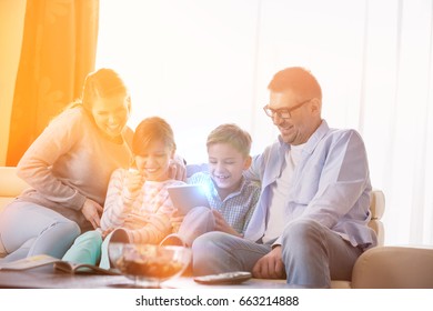 Cheerful Family Using Tablet PC Together In Living Room