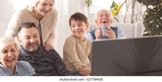 Cheerful family watching TV together during sunday afternoon
