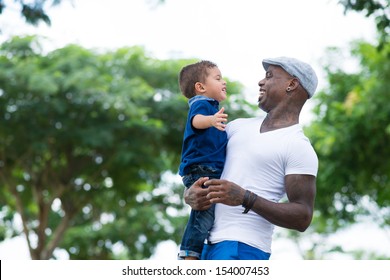 A cheerful father holding his son on hands in the park 