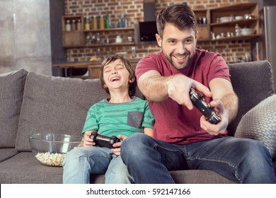 cheerful father and son playing video game at home