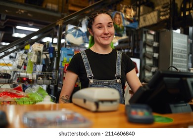 Cheerful female cashier smiling at camera in store