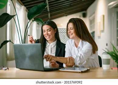 Cheerful female colleagues using laptop together