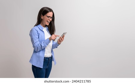 Cheerful female entrepreneur in glasses laughing and pointing at smart phone over white background - Powered by Shutterstock