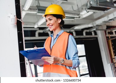 Cheerful Female Firefighter Standing Near Fire Alarm While Holding Clipboard