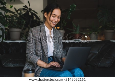 Cheerful female freelancer enjoying remote working on laptop computer using 4g wireless for creating graphic design, smiling woman writing text for sharing to social media networks via netbook app