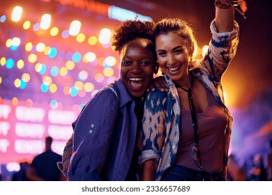 Cheerful female friends dancing in front of music stage during summer festival and looking at camera.  - Powered by Shutterstock