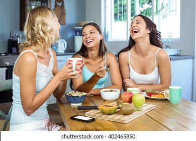 Cheerful female friends having breakfast at table in house - Powered by Shutterstock