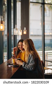 Cheerful female friends sitting together at cafe table. Smiling women meeting in a coffee shop and chatting. - Shutterstock ID 1822030109