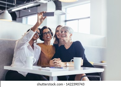 Cheerful female professionals taking a selfie during break in office. Group of businesswomen taking a self portrait with mobile phone. - Shutterstock ID 1422390743