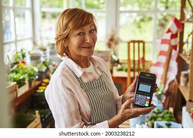 Cheerful Female Showing Pos Terminal In Her Rural Shop