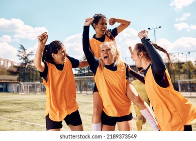 Cheerful female soccer players shouting while celebrating after the match on playing field. - Powered by Shutterstock