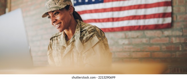 Cheerful female soldier smiling while video calling her family on a laptop. American servicewoman communicating with her loved ones while serving her country in the army. - Shutterstock ID 2213290699