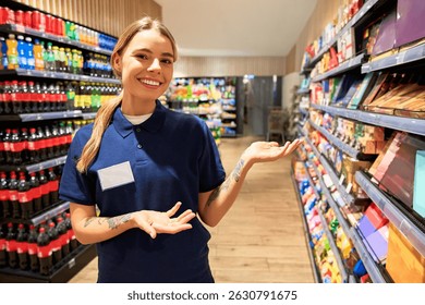 Cheerful female store worker in uniform smiling and gesturing toward supermarket shelves. Concept of customer service, helpful staff, product promotion and retail shopping experience. - Powered by Shutterstock - Get 15% off with code: PIKWIZARD15