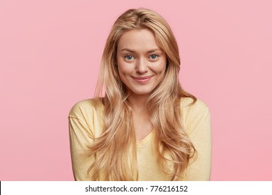 Cheerful female student with dimples on cheeks, rejoices successfully passed exams, glad to have meeting with groupmates. Delighted beautiful pleased woman has attractive look, poses in studio