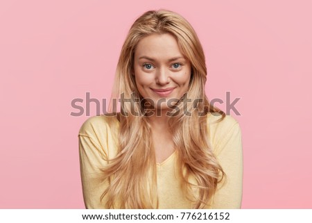 Cheerful female student with dimples on cheeks, rejoices successfully passed exams, glad to have meeting with groupmates. Delighted beautiful pleased woman has attractive look, poses in studio