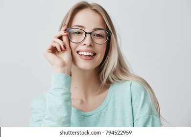 Cheerful female student in stylish eyewear rejoices successfully passed exams, glad to have meeting with groupmates. Delighted beautiful pleased woman has attractive look, poses indoors. - Powered by Shutterstock