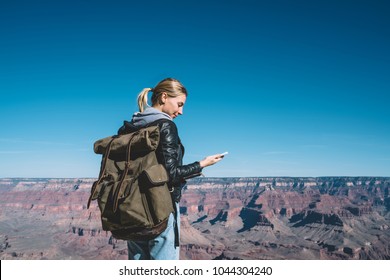 Cheerful Female Traveler With Backpack Using Roaming Data Connection For Blogging During Wanderlust Trip, Smiling Hipster Girl Satisfied With Mobile Network Coverage Connecting With Friend On Cellular