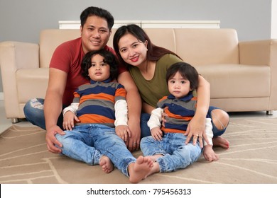 Cheerful Filipino family sitting on the floor in living room
