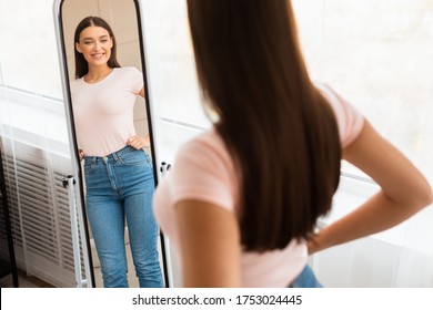 Cheerful Fit Woman Looking At Reflection In Mirror Standing Indoor. Successful Weight Loss Concept. Selective Focus