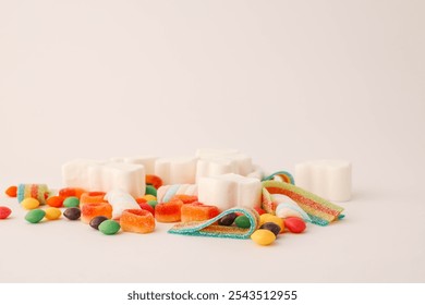 A cheerful flat lay composition of assorted colorful candies and marshmallows arranged on a light background. Featuring rainbow ribbon candy, white marshmallow clouds, colorful chewy balls.