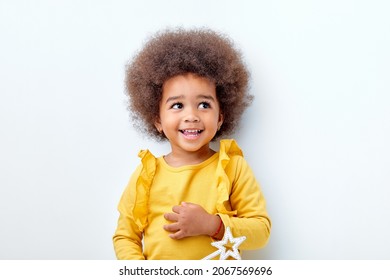 fröhliches, flauschiges, afrikanisches amerikanisches Mädchen, das glücklich aussieht und Zauberstab in Händen hält, lacht, einzeln auf weißem Studiohintergrund. Porträt. Bevölkerungsvielfalt, afrikanische ethnische Zugehörigkeit, Kinderkonzept