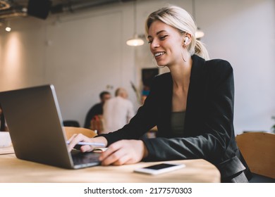 Cheerful freelancer in earbuds watching professional webinar video on digital netbook computer, happy female graphic designer in bluetooth headphones listening audio and browsing web page on laptop - Powered by Shutterstock