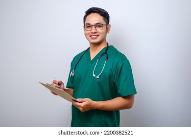 Cheerful friendly asian male physician, doctor with clipboard during daily checkup, standing over isolated white background - Powered by Shutterstock