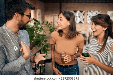 Cheerful friends at the bar standing and having a fun conversation. Two girls and a guy talking. Togetherness, fun, lifestyle concept. - Powered by Shutterstock