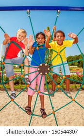 Cheerful friends climbing the net at a city playground