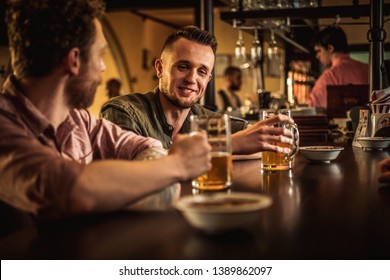 Cheerful Friends Drinking Draft Beer In A Pub