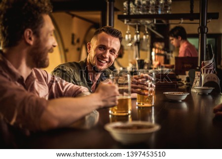 Cheerful friends drinking draft beer in a pub