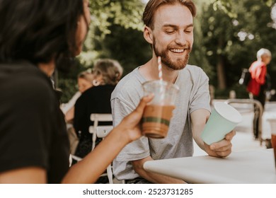 A cheerful friends enjoy a drink at an outdoor café. Two friends relaxed atmosphere with coffee cups, laughter, and friendship in a sunny setting. Friends drinking coffee with smiling at outdoor café - Powered by Shutterstock