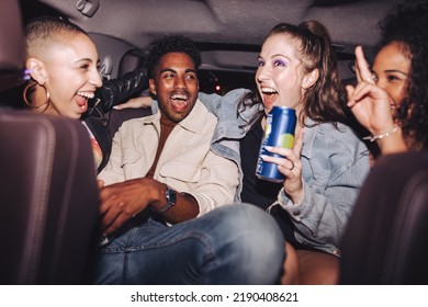 Cheerful Friends Having Fun In The Back Seat Of A Car. Group Of Diverse Young People Laughing Together While Sitting In A Cab. Four Happy Friends Having A Good Time On Their Way Home After A Party.