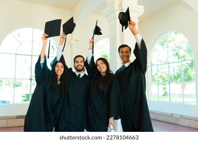 Cheerful friends hugging and looking happy while celebrating after their graduation ceremony at university campus - Shutterstock ID 2278104663