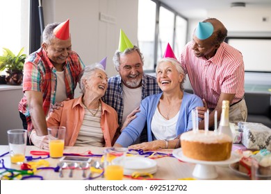 Cheerful friends looking at excited senior woman during birthday party in nursing home - Powered by Shutterstock