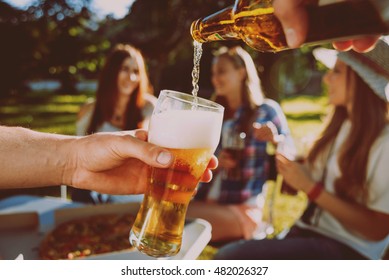 Cheerful Friends On Picnic In The Park. Drinking Beer