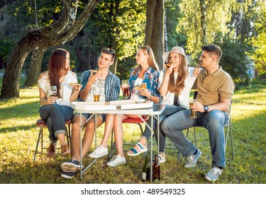 Cheerful friends on picnic in the park. Smiling and talking