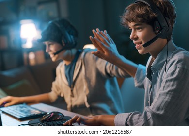 Cheerful friends playing online video games together and winning, they give a high five