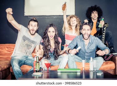 Cheerful Friends Sitting On The Couch And Exulting While Watching A Sport Match On Tv - Happy Young Cool People Having Fun At A Home Party