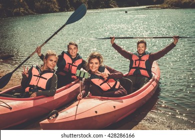 Cheerful Friends Taking Selfie In Kayaks On A Beach.